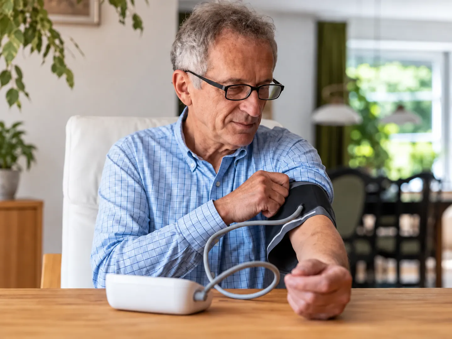 Man fitting a blood pressure cuff around his upper arm at home
